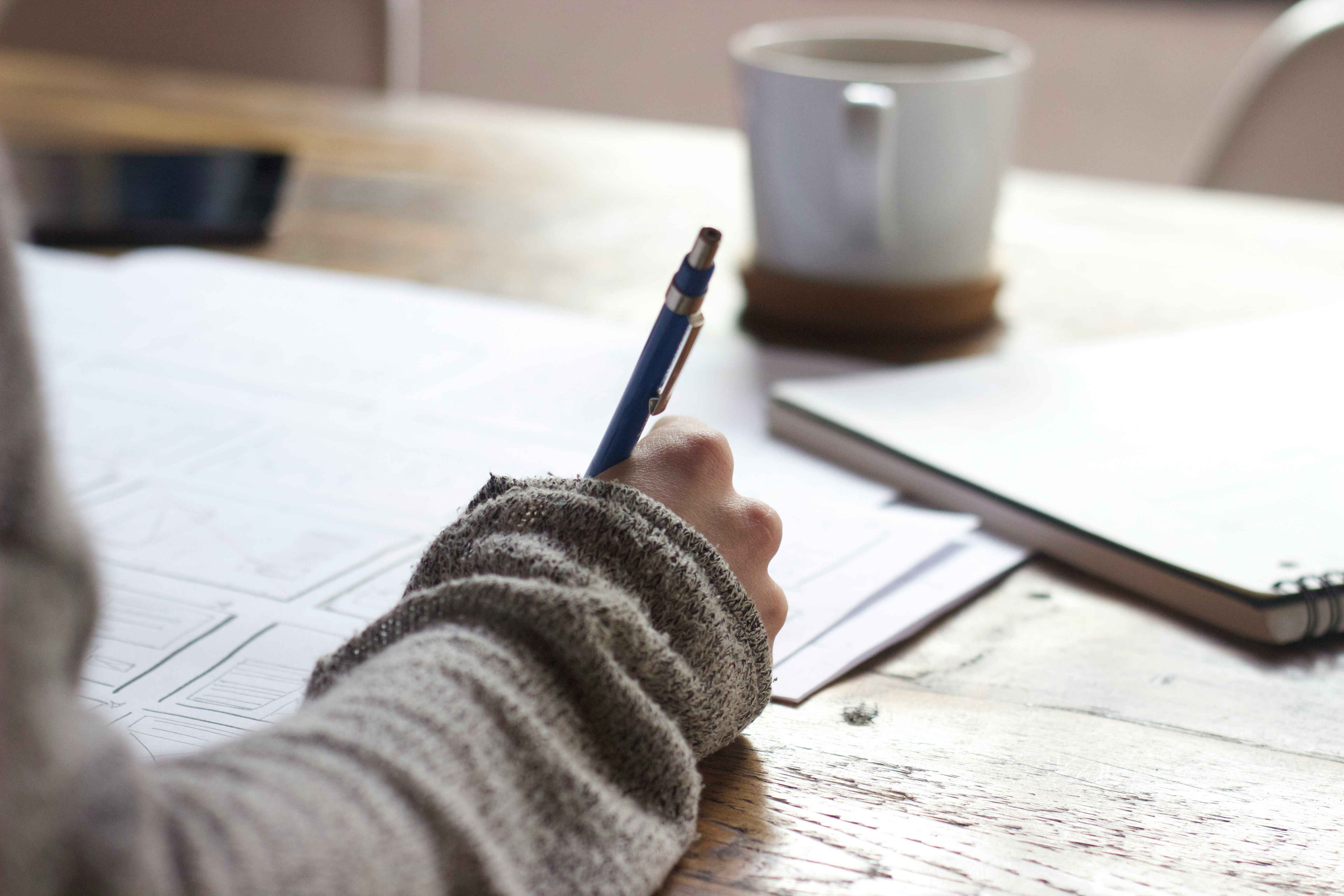 Stock photo of someone writing at a table